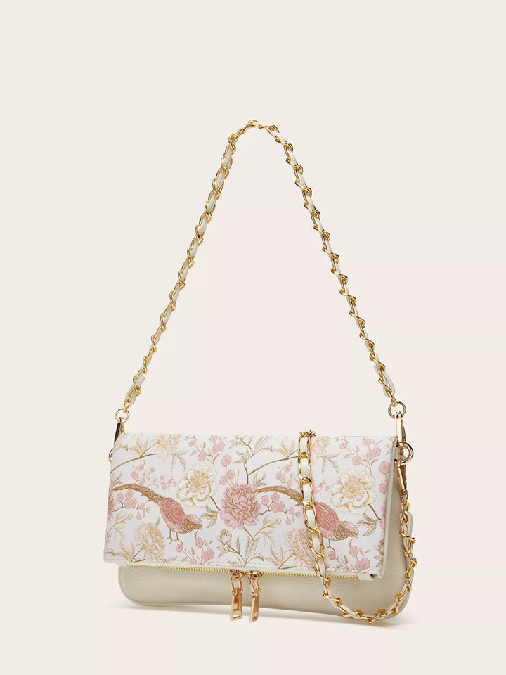 Floral patterned handbag with gold chain strap on a beige background
