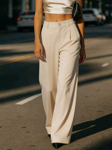 Person wearing beige pants and a white top on a street.