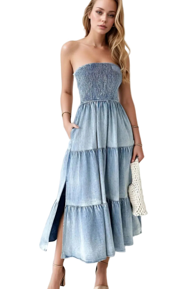 Woman wearing a strapless, tiered denim dress against a white curtain background