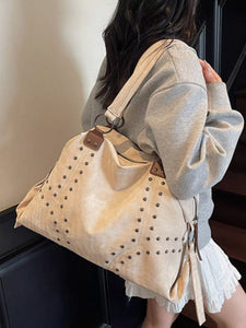 Open beige bag containing a white water bottle, black container, and glass bottle on a light surface.