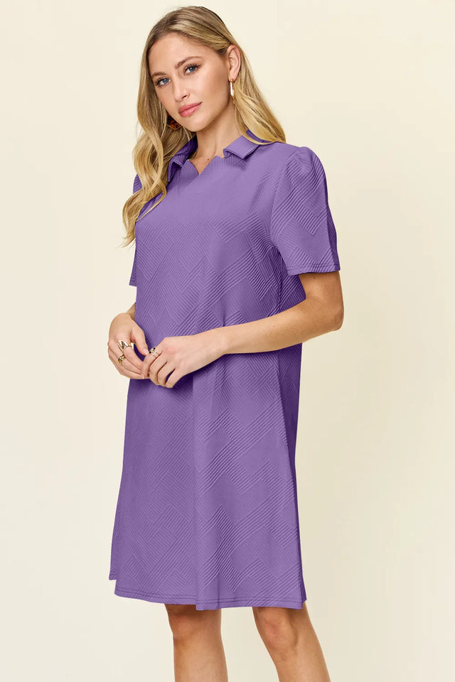 Woman wearing a purple dress with a collar on a beige background
