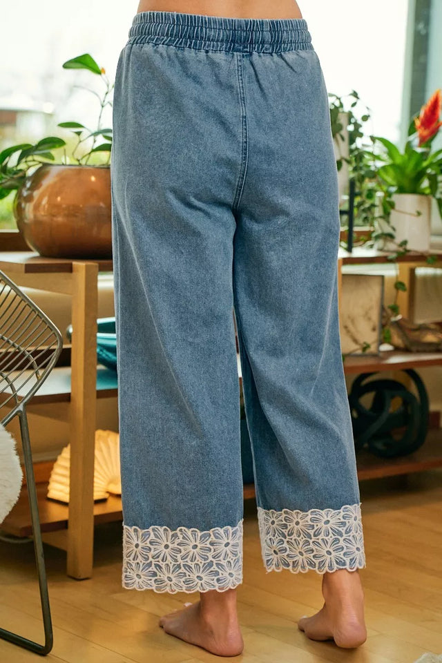 Denim pants with lace cuffs worn by a person indoors.