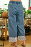 Denim pants with lace cuffs worn by a person indoors.