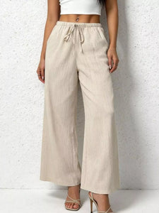 Beige wide-leg pants worn by a person on a white background